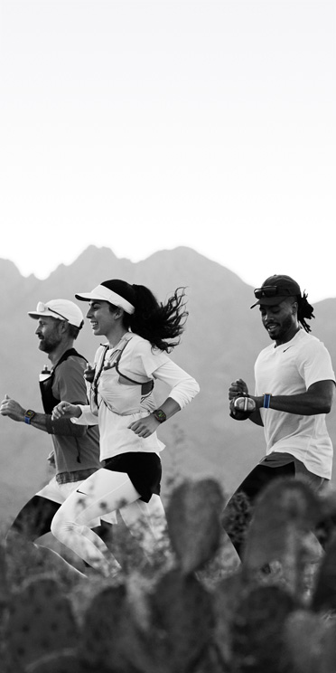 Trys žmonės, bėgantys dykumos taku, stebi savo treniruotes „Apple Watch Ultra 3“ laikrodyje