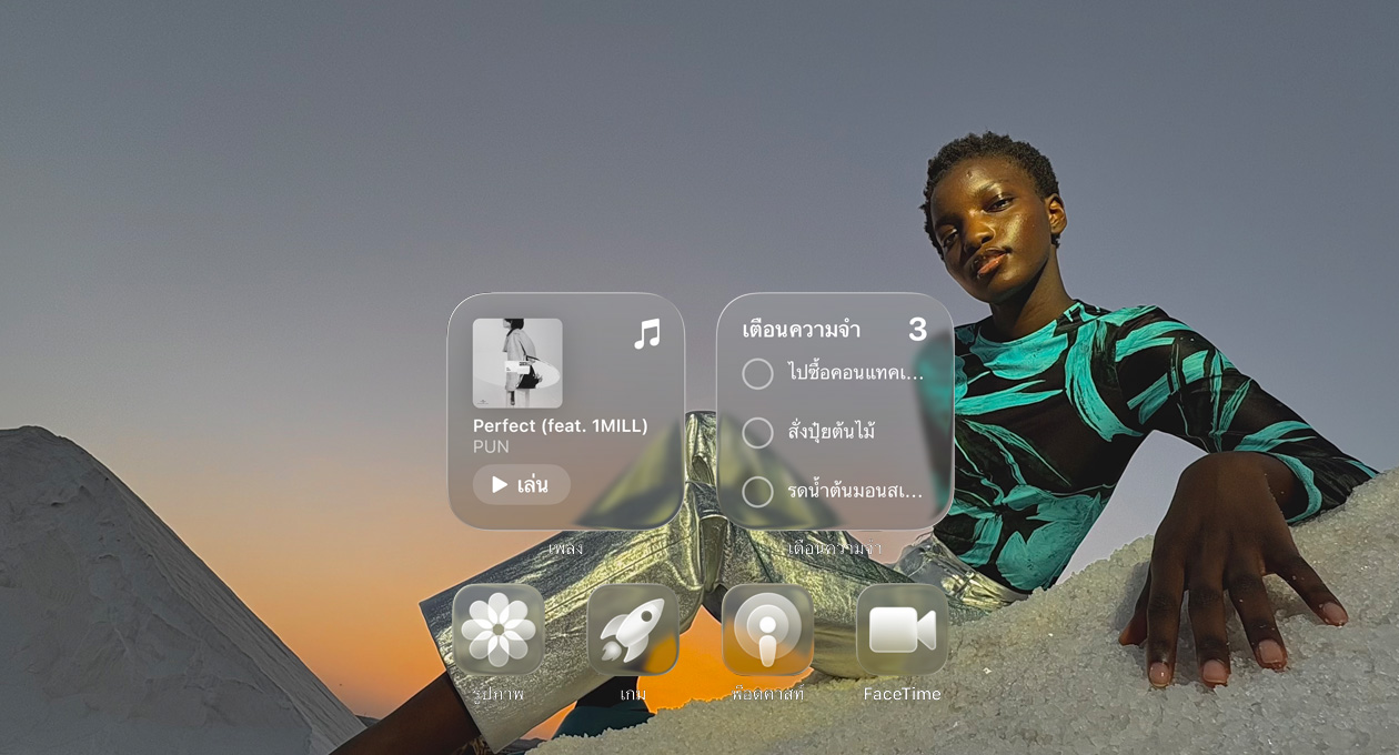 จอภาพแบบ Liquid Glass พร้อมไอคอนแอปแบบใส เช่น Apple Music, เตือนความจำ, รูปภาพ, เกม, พ็อดคาสท์ และ FaceTime ที่หักเหกับภาพพื้นหลัง