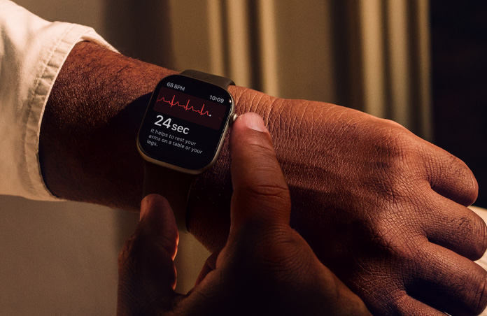 A person presses and holds the Digital Crown on Apple Watch Series 11 to measure heart health in ECG app