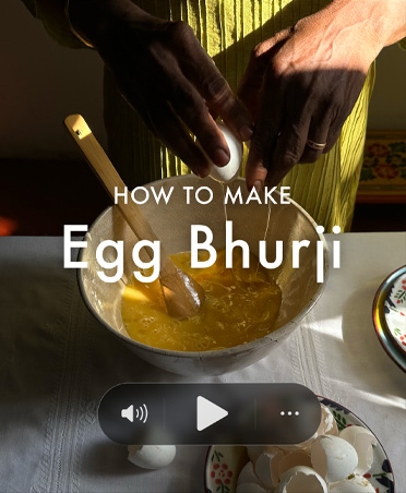 Still from a cooking video, man breaking eggs into a bowl