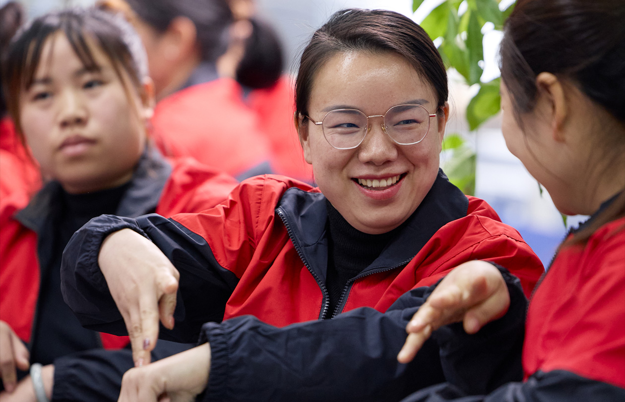 Three employees sit together as one signs to another