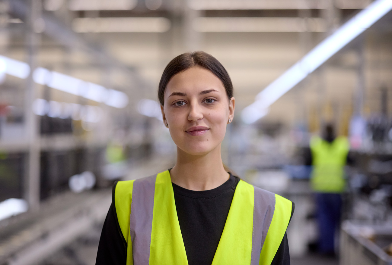 An employee wearing a high-visibility vest looks at camera
